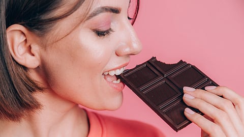 A woman eating a dark chocolate bar.