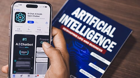 A person uses an iPhone showing an AI chatbot app, with an AI book in the background.