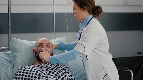 A doctor adjusts an oxygen mask for a patient in a hospital bed.