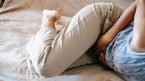 A girl holding her stomach in pain.