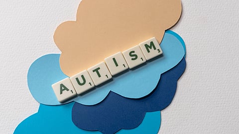 Paper cutouts spelling "AUTISM" on a light background.