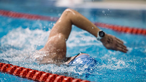 An action shot of a swimmer mid-stroke in a pool lane.
