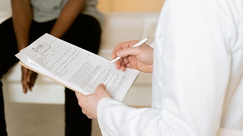 A doctor in a white coat holding a clipboard and pen.