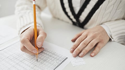 A student fills out a multiple-choice answer sheet with a pencil during an exam.