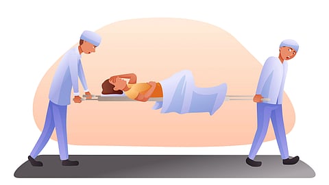 Two healthcare workers carry a patient on a stretcher.
