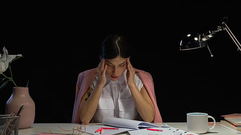 A woman in stress with hands on her temple.