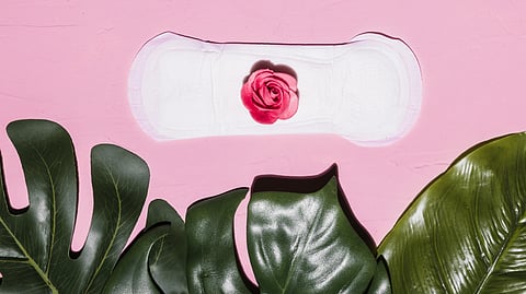 A sanitary pad with a pink rose on a pink background.