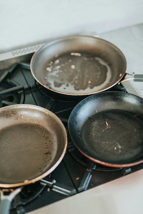 Worn, discolored non-stick pans showing coating damage on a stovetop