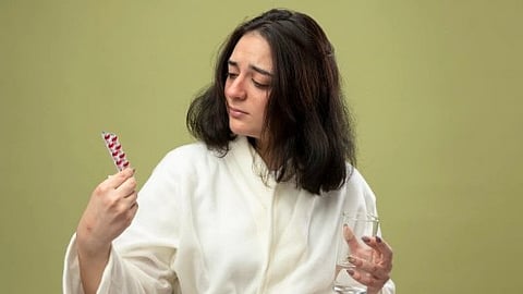 A girl holding red vitamins for hair.