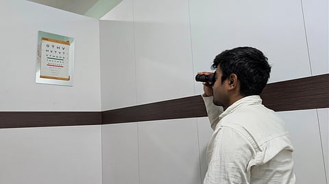An eye doctor examines a patient's eye with a handheld ophthalmoscope.