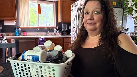 A woman sits beside a basket filled with medicine and supplement bottles.