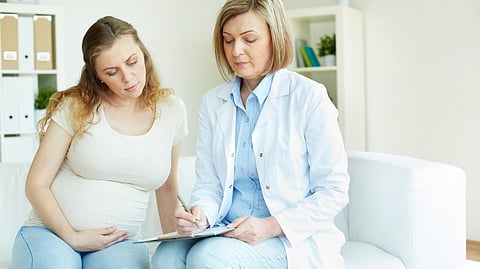 A doctor talks with a pregnant woman during a prenatal check-up.
