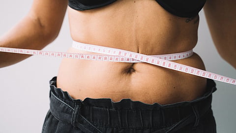 A person holding a measuring tape around her waist.