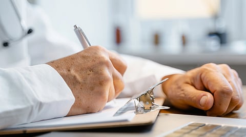 A doctor writes notes on a clipboard.