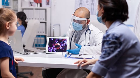 A doctor shows a medical image on a tablet to a child and caregiver during a consultation.