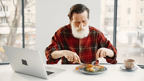 An older man enjoys a meal while sitting at a table.