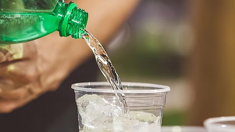 A drink is poured into a cup with ice and mint.