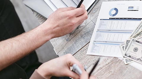 An overhead close-up of hands reviewing printed documents on a closed laptop.