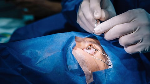 A surgeon performs an eye procedure on a patient.