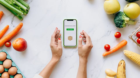 An overhead view of hands holding a smartphone on a marble table.
