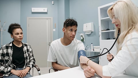 A healthcare professional checks a young man's blood pressure.