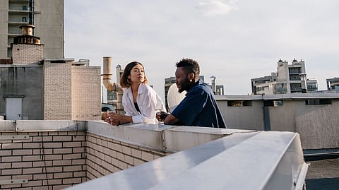 A man and woman talk together on a rooftop.