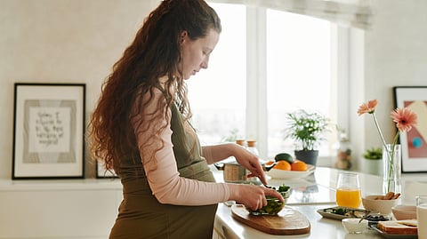 A pregnant woman prepares a healthy meal in her kitchen.