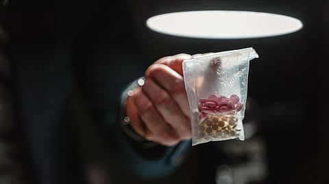 Hand holding a pouch containing assorted tablets.