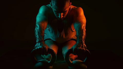 A man performs a push-up using kettlebells.