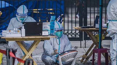 Healthcare workers in protective suits at a testing site.
