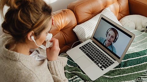 A woman consults a doctor through a video call from her couch.
