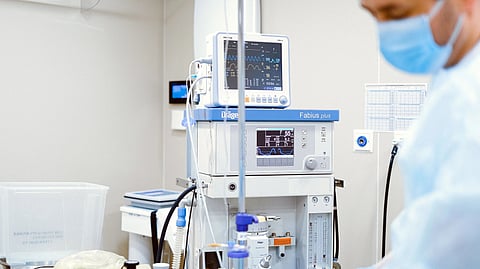 A doctor stands beside a patient monitor in the ICU.