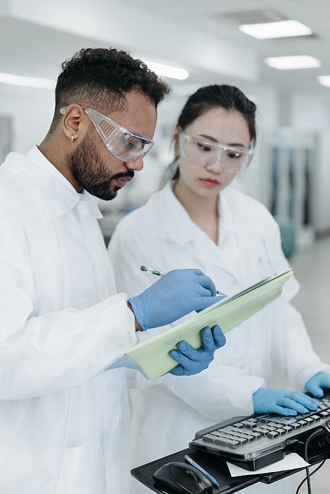 Two Lab doctors in lab coats and safety goggles reviewing and validating a diagnostic report together