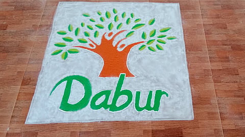 A colorful Dabur logo made with rangoli on a tiled floor.