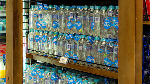 Bottled water is neatly arranged on wooden shelves.