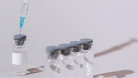 Four medical vaccine vials are arranged in a row.