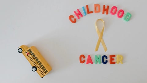 A yellow ribbon with the words “Childhood Cancer” on a white background.
