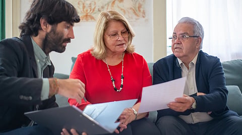 An elderly couple reviews insurance documents with a financial advisor.