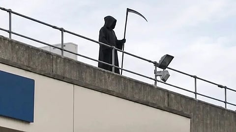 Leon Gillespie standing on the roof of Ysbyty Glan Clwyd Hospital in Wales wearing a black hooded costume during the June 6 hospital incident.