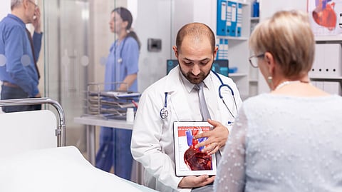 Doctor shows a heart scan to an older woman in a hospital room.
