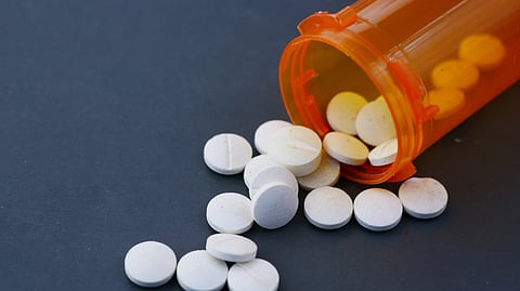 Medicine tablets spilling from an orange container.