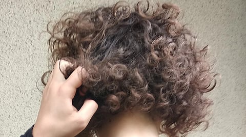 Person affected by trichotillomania (hair pulling disorder), while pulling out her hair.