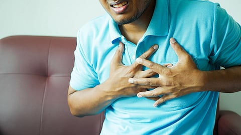 A close-up image of a man clutching his chest, indicating heart pain or discomfort