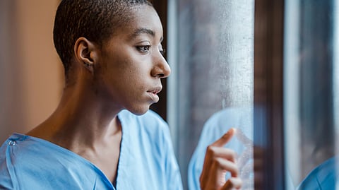 Anxious woman by the window in patient gown
