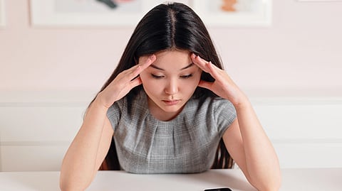 A girl sitting on desk, looking stressed.