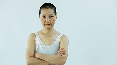 Asian woman with short hair wearing a pink ribbon, representing breast cancer awareness and resilience