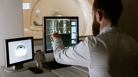 Physician analyzing imaging scans of a vertebrae on a screen