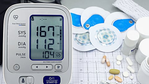 A close-up shot of medical equipment including blood pressure monitor and pills on an ECG graph