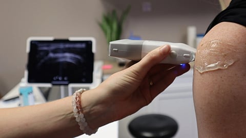 Doctor performing a shoulder ultrasound in a medical office with modern equipment