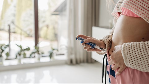 Focused woman administering insulin with pen in a home setting, emphasizing health care and hormonal  management